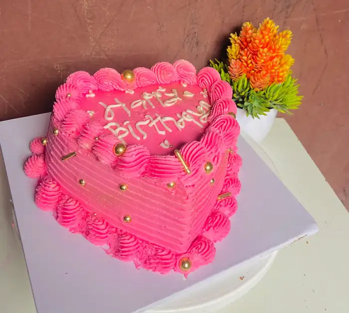 Pink heart-shaped Happy Birthday cake with gold pearls and piped rosettes