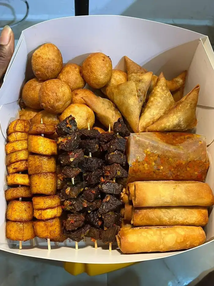 Small chops box with puff-puff, samosa, spring rolls, peppered meat and plantain skewers
